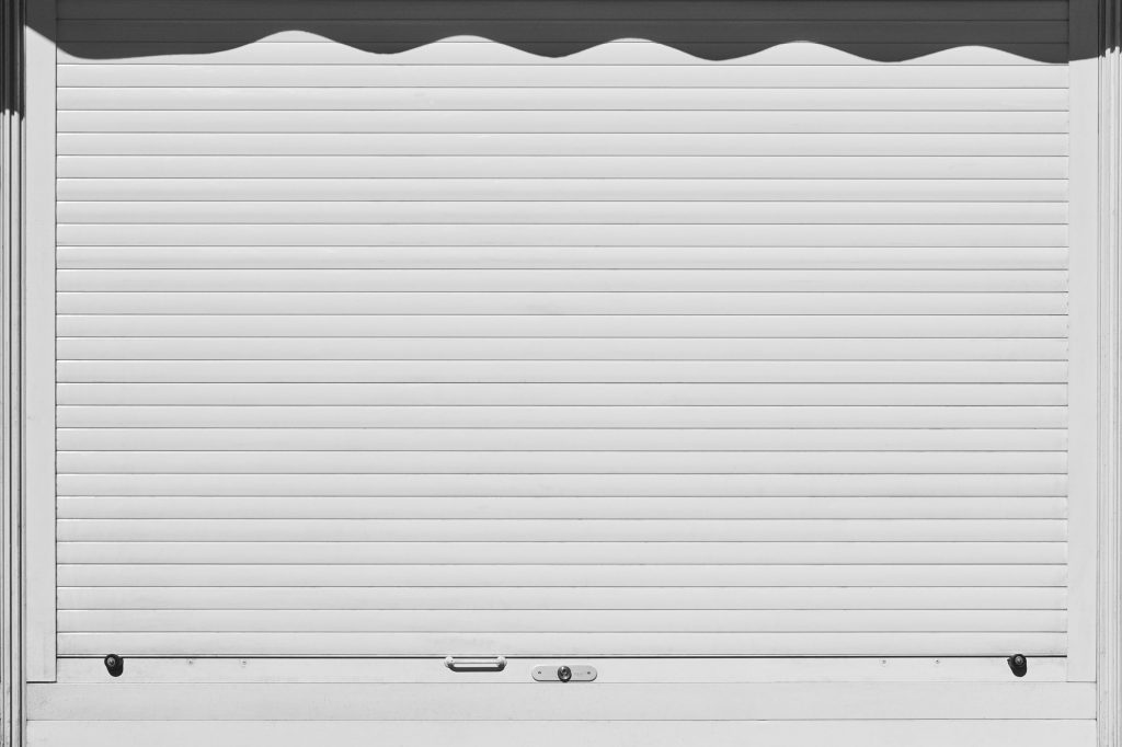 Closed and locked white rolling shutter. Security background. Horizontal