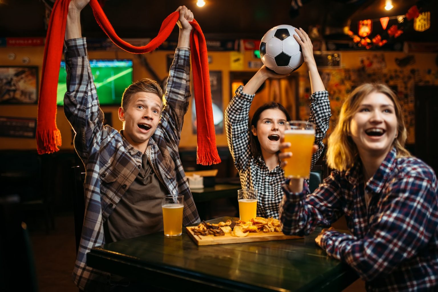 Football fans with scarf and ball in sports bar